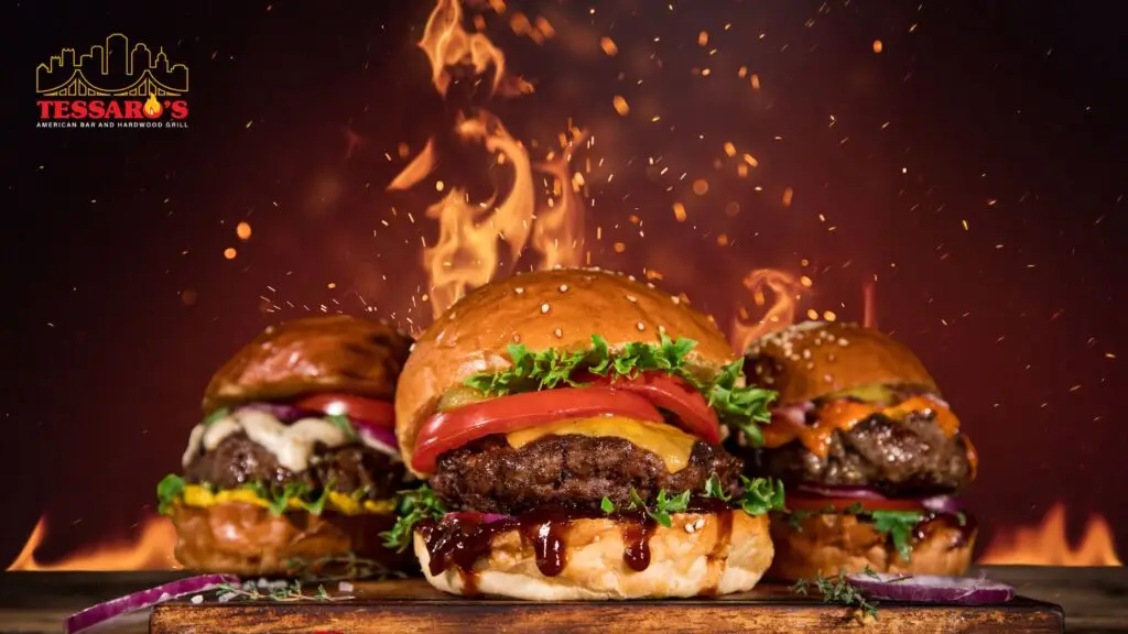 Three hardwood-grilled burgers with flames at Tessaro's American Bar and Hardwood Grill in Pittsburgh, PA